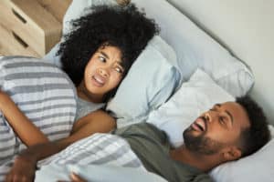 Shot of a young woman getting irritated with her husband's snoring in bed