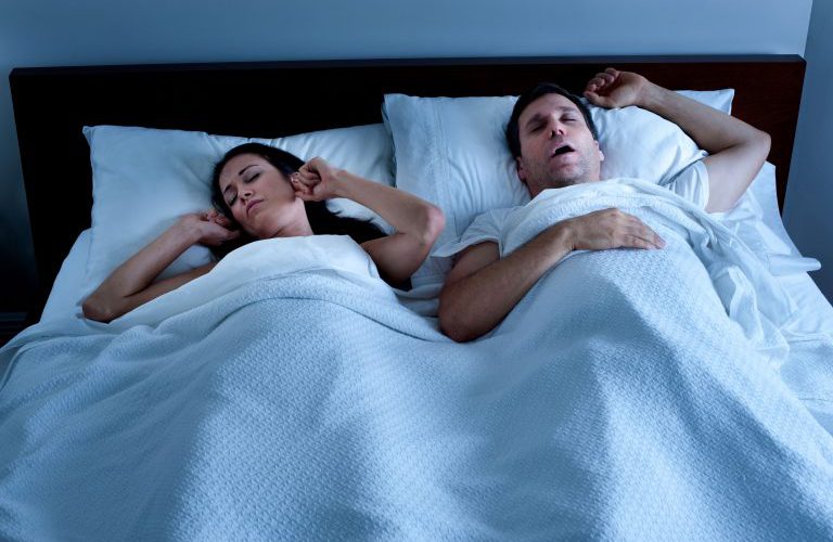 A woman struggling to sleep while man snores