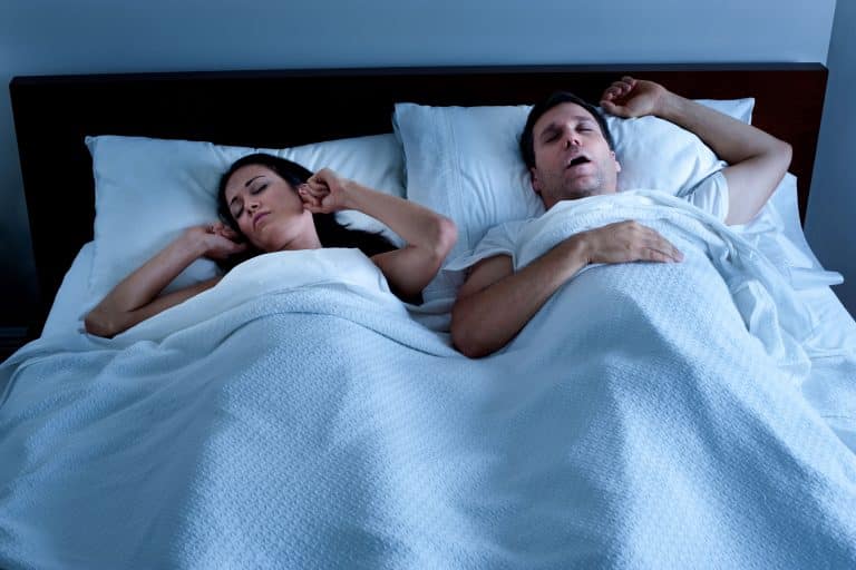 A woman struggling to sleep while man snores