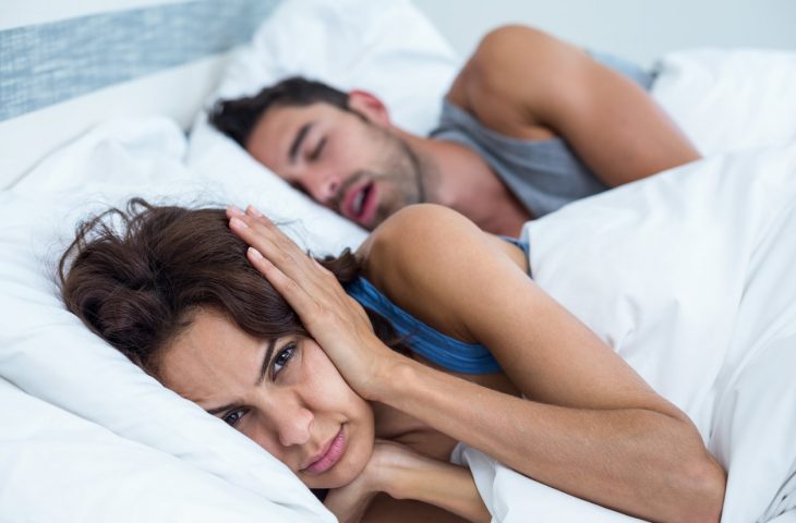woman covering her ears because of snoring husband