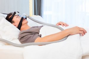 man sleeping in bed with CPAP mask