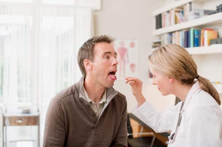 Doctor examining patients throat in doctors office