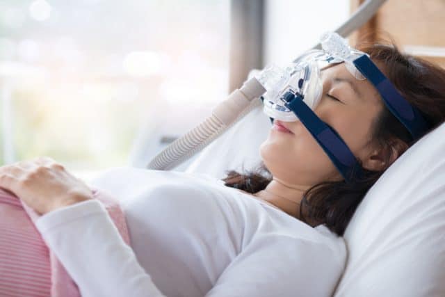 woman wearing CPAP mask to sleep