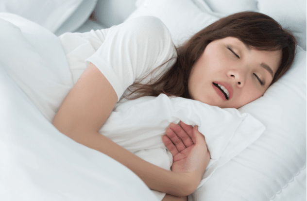 portrait of stressful, exhausted woman snoring while sleeping on bed in bedroom environment