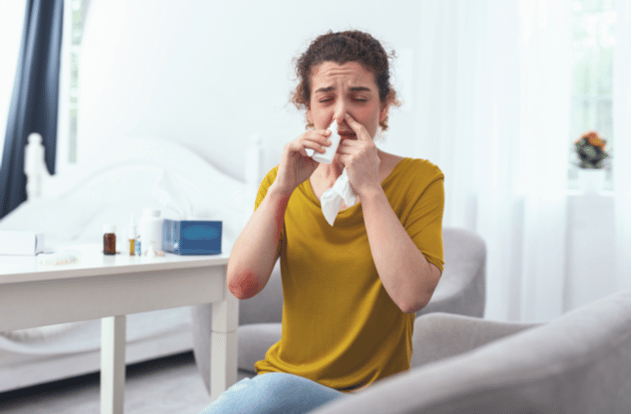 woman-sitting-on-couch-while-using-nasal-spray-for-her-runny-nose