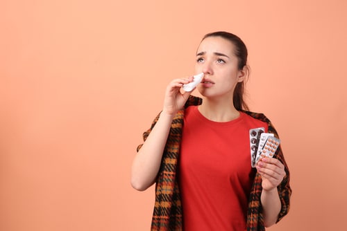 Woman with pills using nasal spray